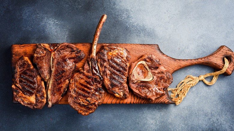 Different cuts of grilled steak on board