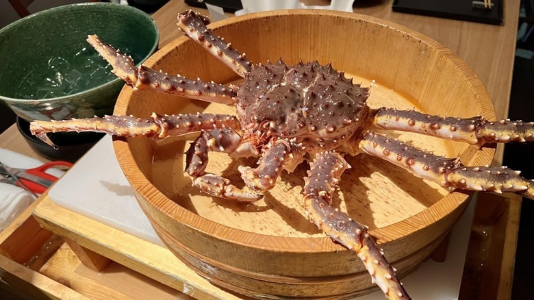 Large crab in a wooden container on a table.