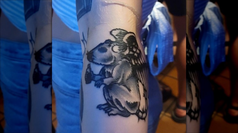 A bar patron with a Silhouette Cocktail Lounge tattoo of a winged rat holding a beer