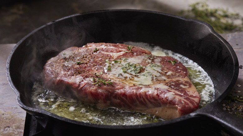 Steak cooking in cast-iron skillet