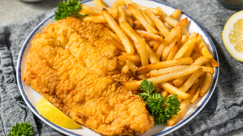 Fried catfish served with french fries, parsley, and lemon