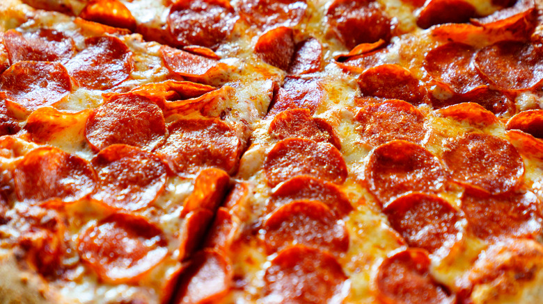 A whole pepperoni pizza, perfectly glazed and glistening with grease, fully sliced