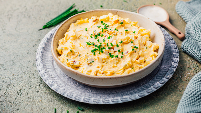 Egg salad filling in a bowl with fresh chives on top