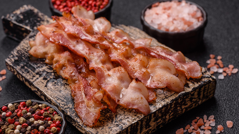 Strips of crispy bacon are arranged on a wooden board.