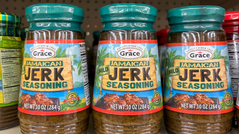 Three bottles of Grace Jamaican Jerk Seasoning on a grocery store shelf.