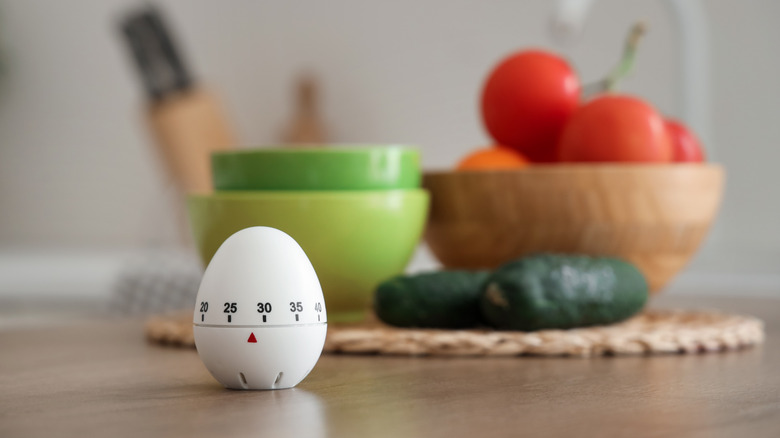 A cute little egg timer is pictured on a kitchen counter.