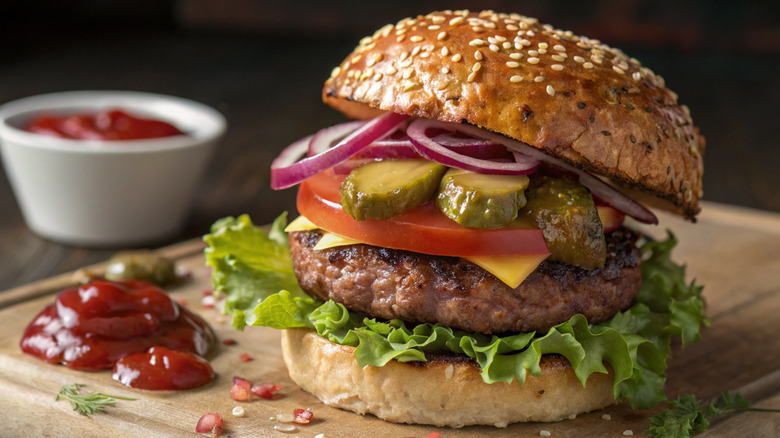 A juicy burger with tomatoes, cheese, lettuce, onion, and pickles