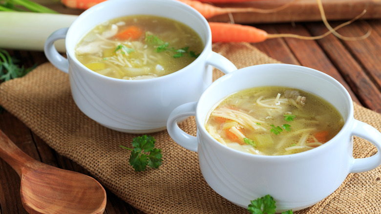 Two white bowls of chicken noodle soup