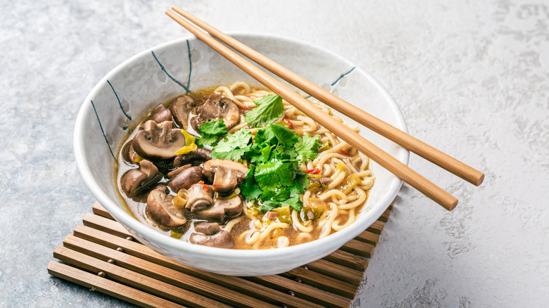 Chopsticks resting on a bowl of ramen with toppings