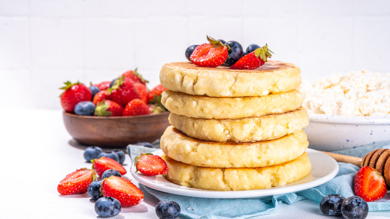 Cottage cheese pancakes with fresh fruit on blue napkin.