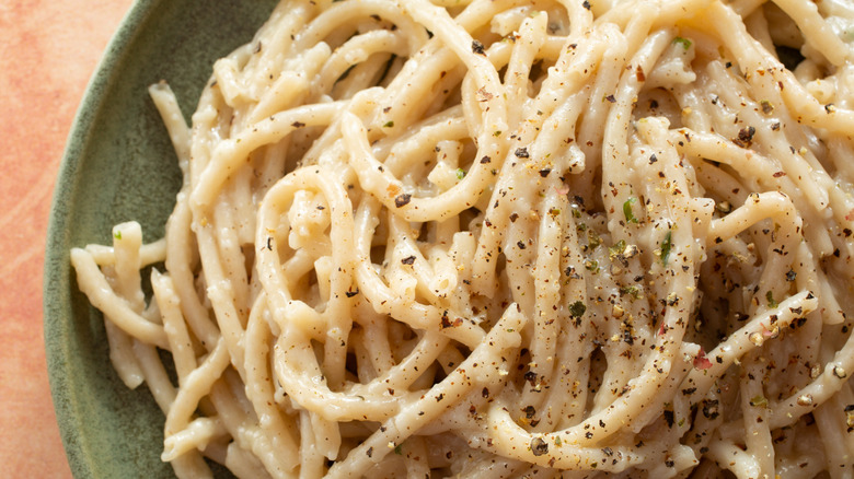 A green plate of cacio e pepe pasta.