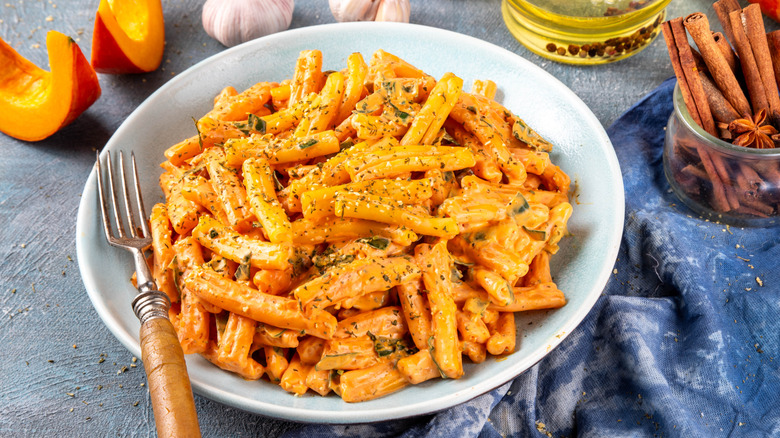 a bowl of creamy pumpkin pasta garnished with black pepper