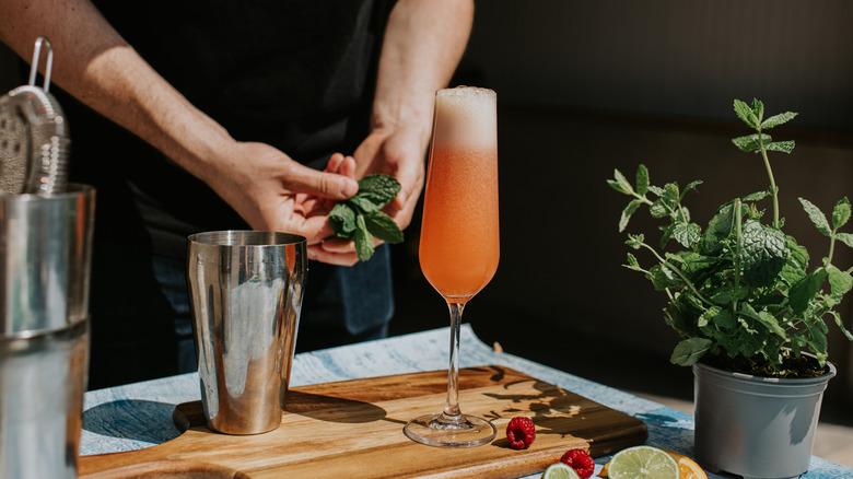 bartender making a fruity sparkling cocktail in a flute glass