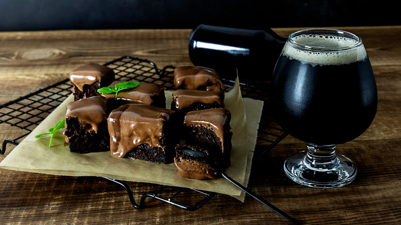 A glass of stout beer next to slices of chocolate cake on a table