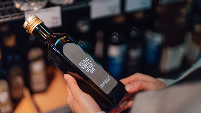 Hands holding a bottle of olive oil in a store