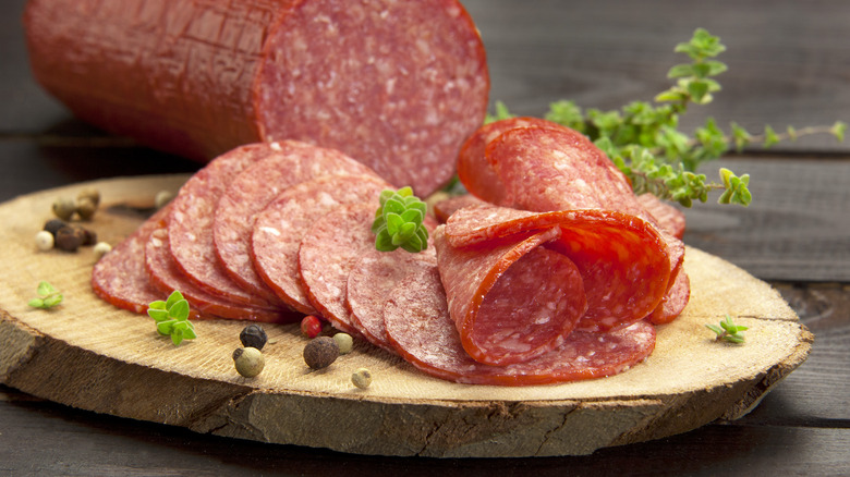 Slices of salami are arranged on a rustic platter.