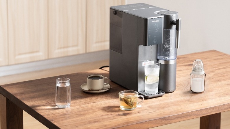Waterdrop Filter A2 system on wooden table with cups of water, tea, and coffee