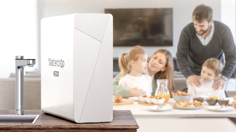 Waterdrop Filter X12 Pro next to sink faucet with family eating dinner in the background