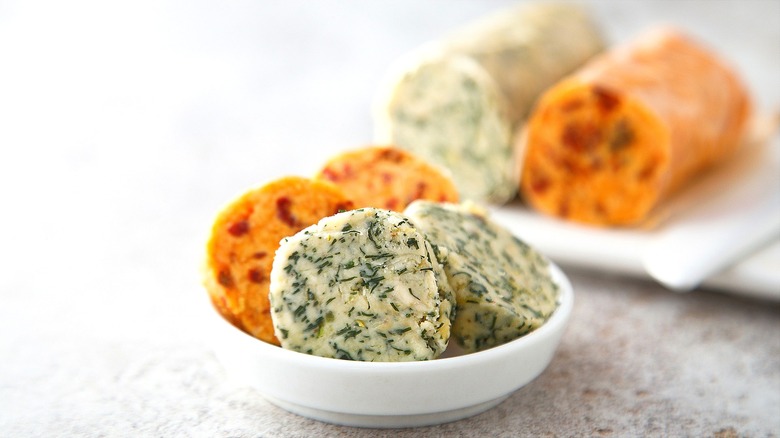 Discs of flavored butter in a small white bowl