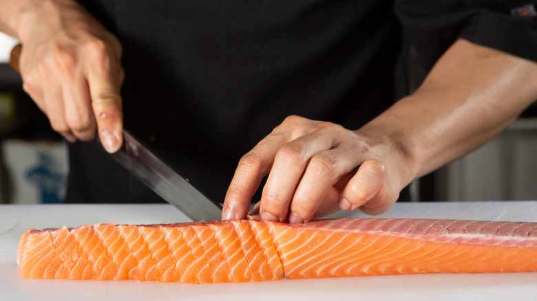 Chef slicing salmon for sushi