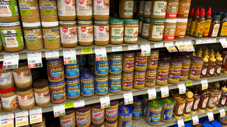 A close-up of grocery store shelves with peanut butter and other items