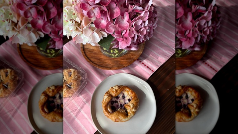 One Costco Blueberry Caramelized Cheesecake Croissant on a white plate over a pink-striped tablecloth