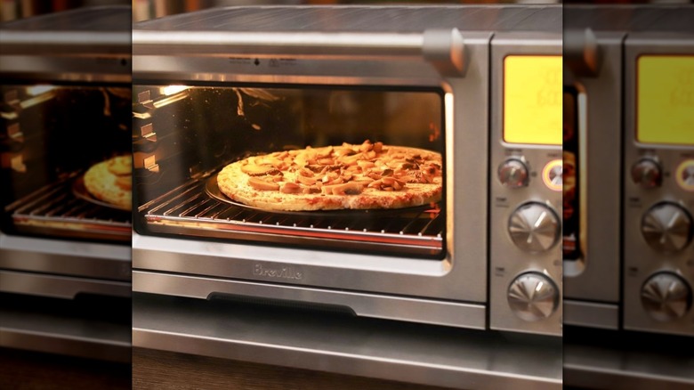 Breville air fryer oven with pizza cooking inside.