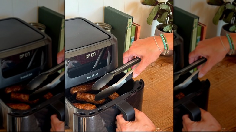 Instant Pot air fryer on counter with woman reaching in with tongs.