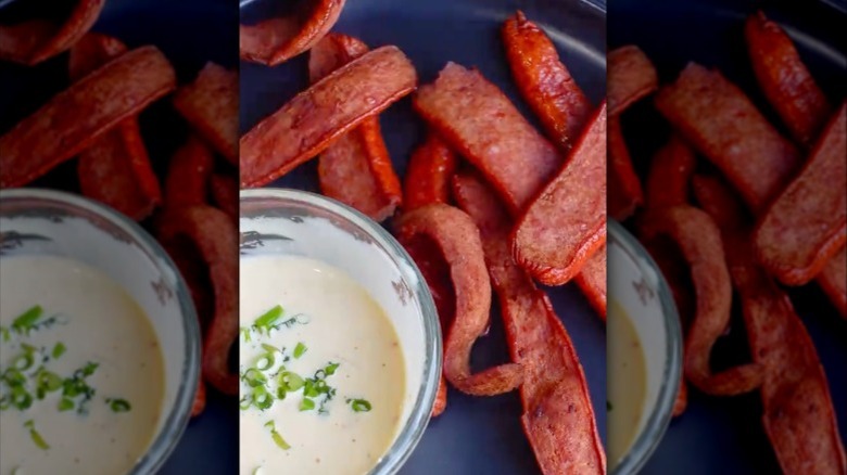 Hot dog chips on a plate with a small glass bowl of dipping sauce