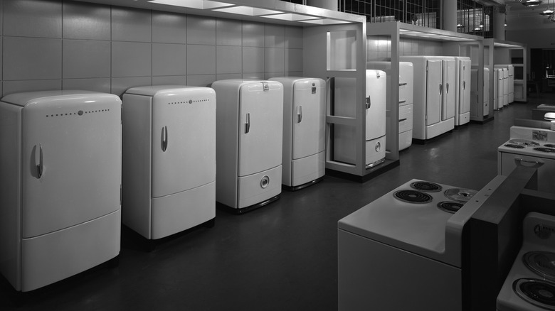 A black-and-white image of various refrigerators in a store