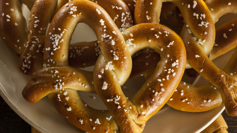 Soft baked pretzels with rock salt stacked on a plate.