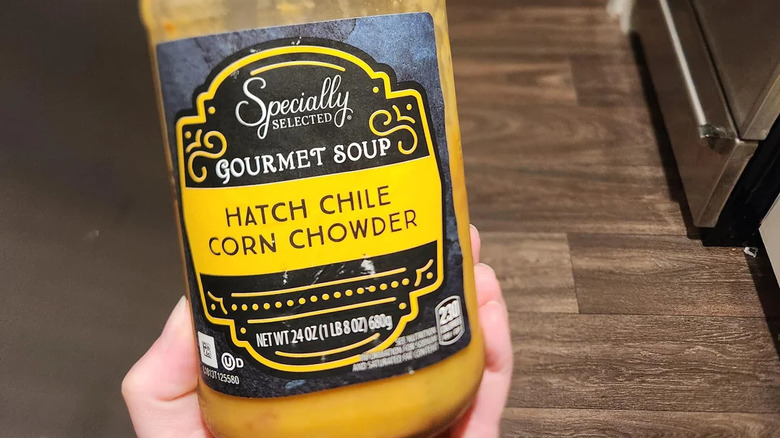 Someone holds a jar of Aldi's Specially Selected brand Hatch Chile Corn Chowder
