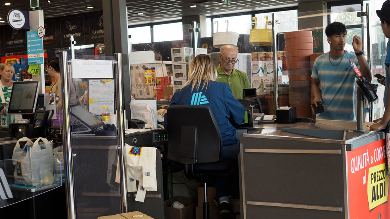 Aldi cashier sitting in a chair while ringing up customers
