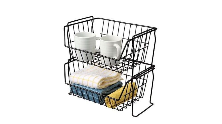 Two Aldi black baskets stacked on top of each other with cloths and mugs.