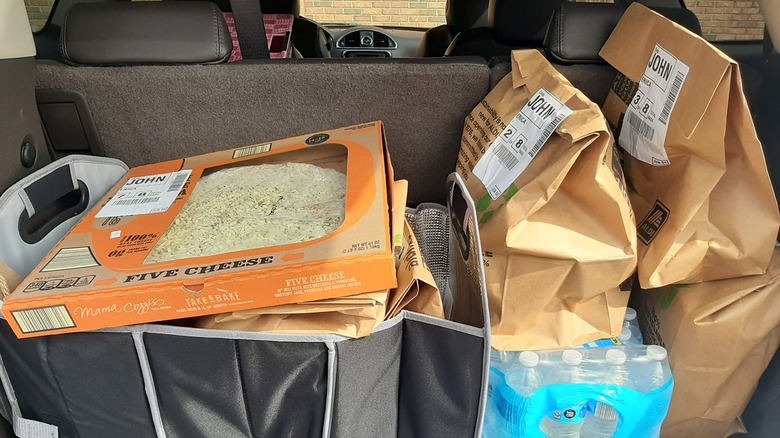 Aldi groceries lay piled in the back of a car trunk