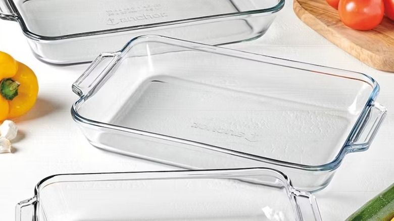 Three clear bakiing dishes arranged around a yellow pepper, tomatoes, and garlic.