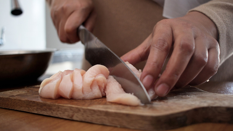 woman cutting chicken breast meat