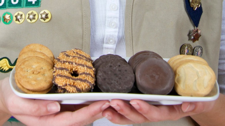 Girl Scout's hands holding a platter of assorted cookies