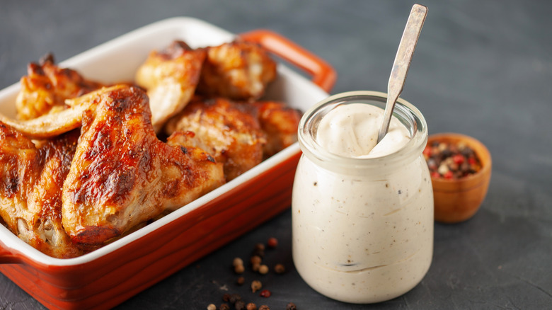 A jar of Alabama white barbecue sauce next to a dish of barbecue chicken