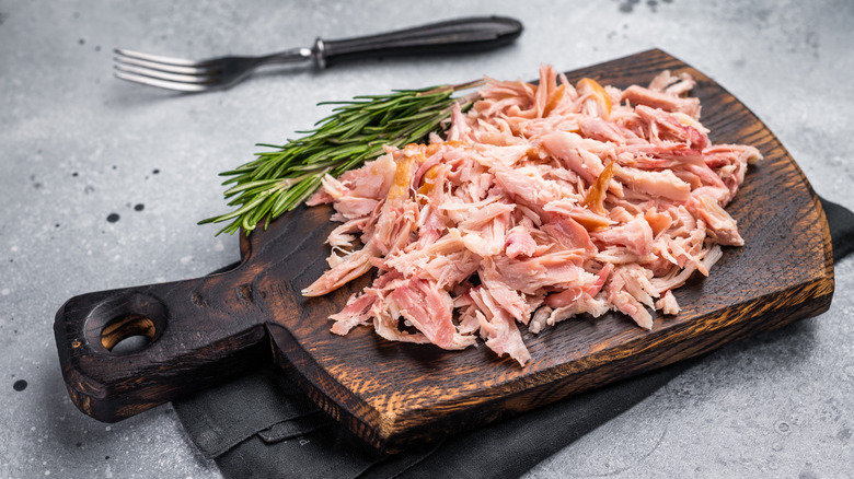 Shredded chicken on a wooden cutting board.