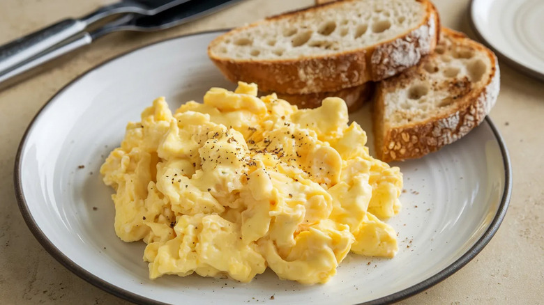 Scrambled eggs are plated with bread