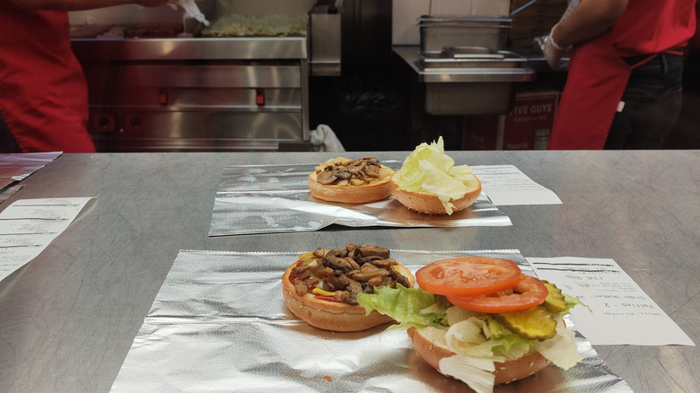 Burgers and toppings being prepared inside a Five Guys restaurant