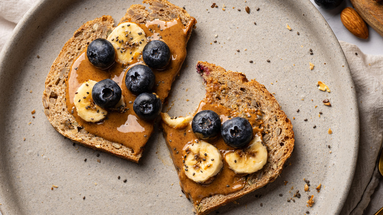 Sourdough bread toasts, topped with almond butter, blueberries, banana and chia seed in table.