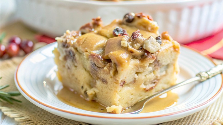A piece of bourbon bread pudding on white plate with spoon