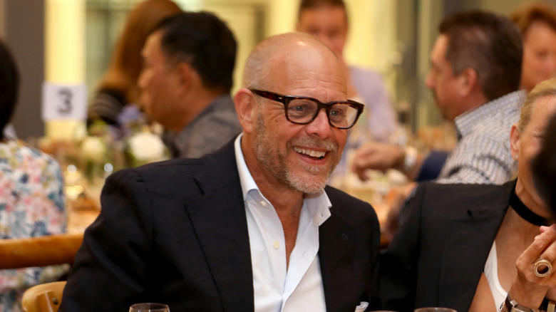 Alton Brown seated at a table smiling