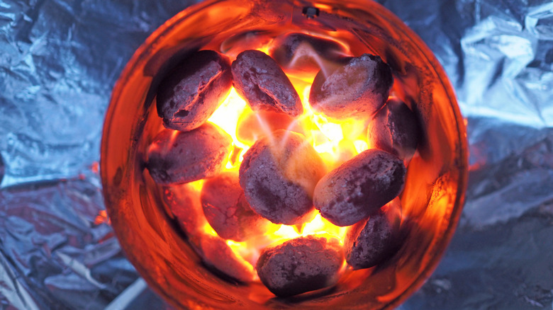 A chimney starter loaded with flaming charcoal briquettes