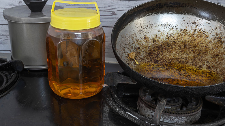 Jar of oil on stove top with dirty pan