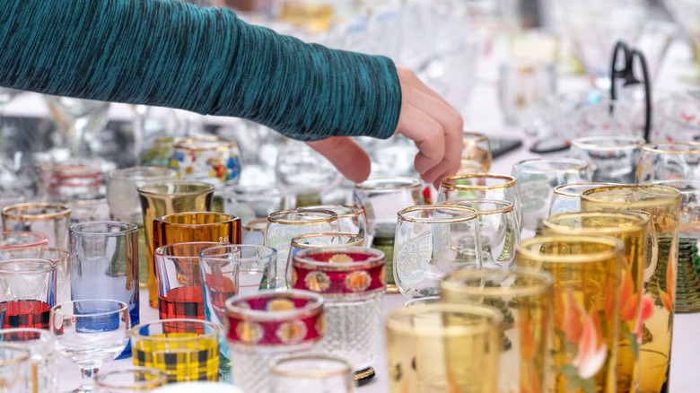 Person reaching to grab a piece of glassware while shopping at a thrift store