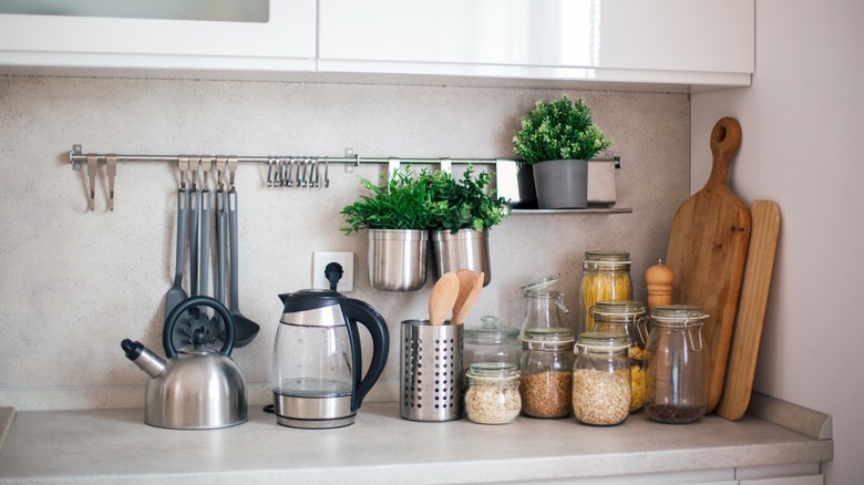 Kitchen countertop with kettles and dry grains displayed in stylish storage containers.
