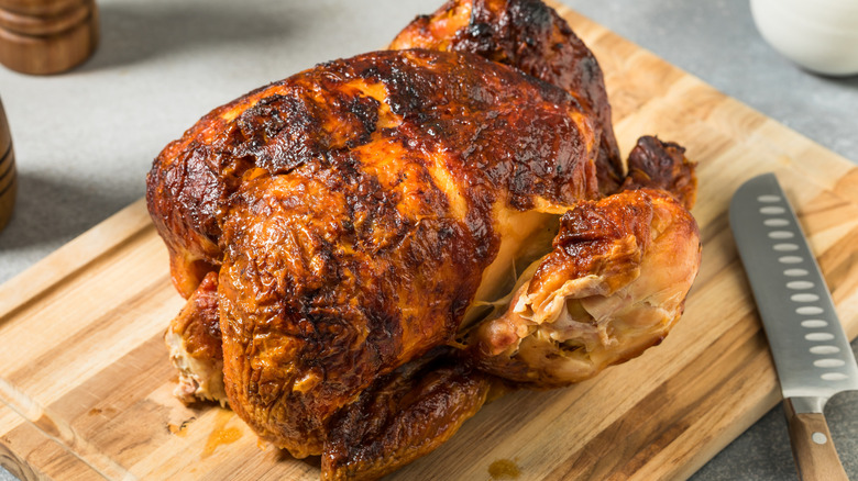 A rotisserie chicken on a cutting board.